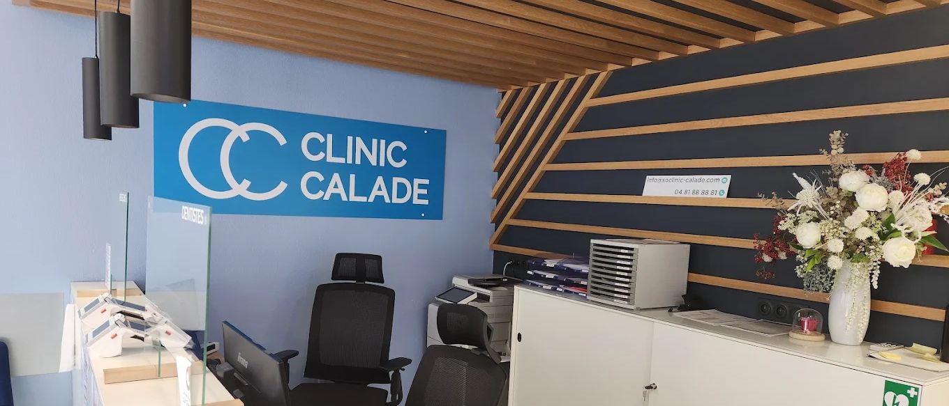 L'accueil du centre : comptoir blanc, enseigne Clinic Calade sur mur bleu et habillage en lattes de bois