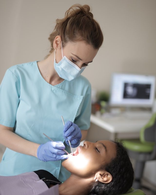 Une chirurgienne-dentiste examine une patiente installée dans le fauteuil